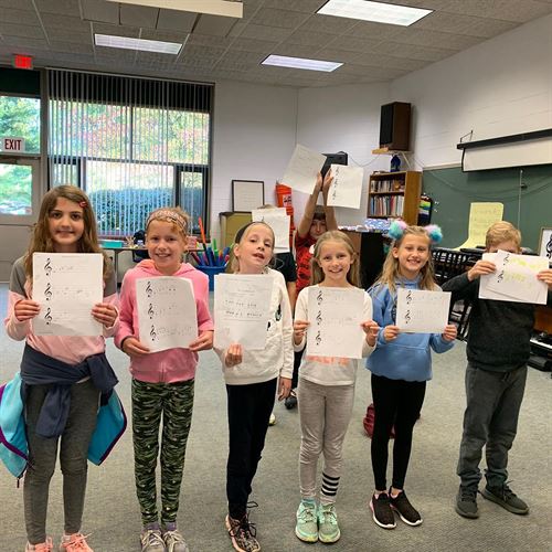 6 elementary students holding music sheets